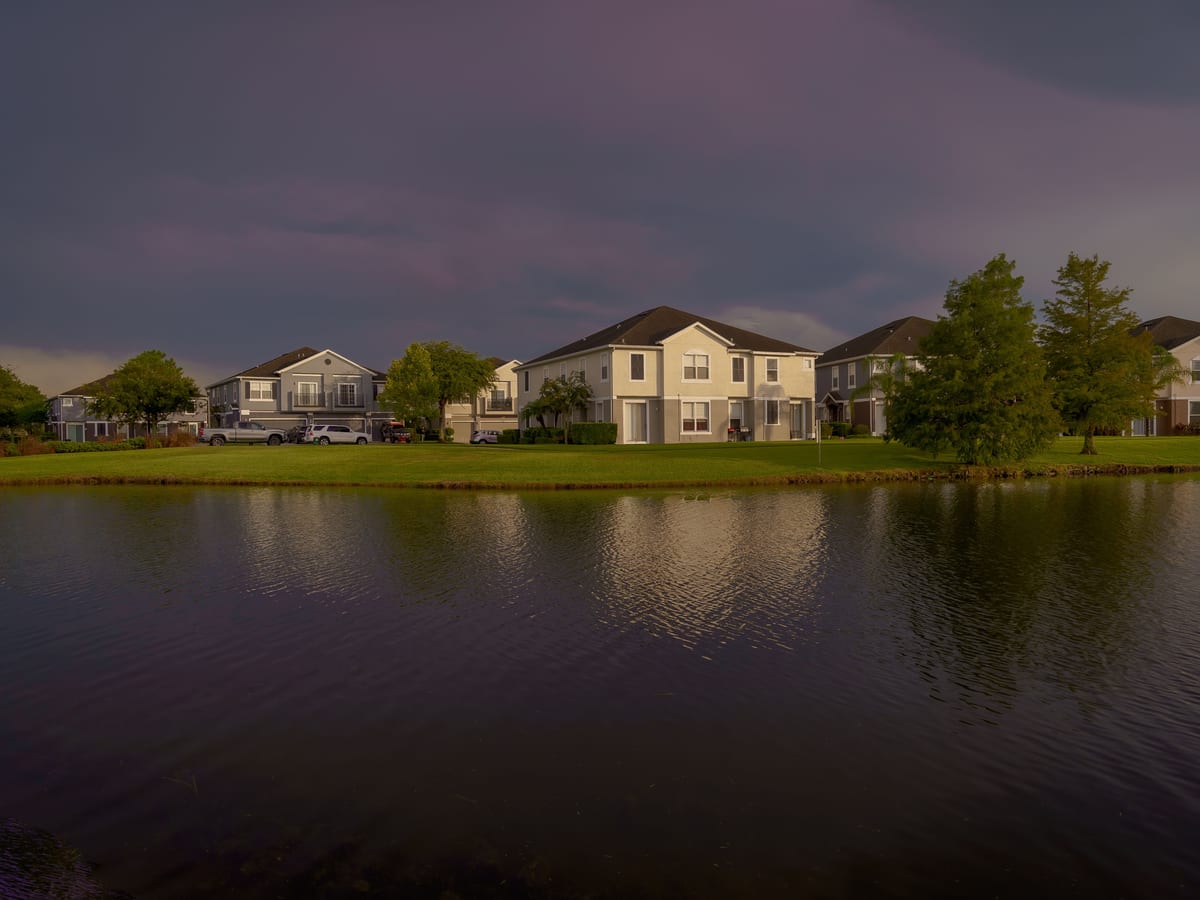 Scenic view of lakefront homes reflecting on water under a dramatic sky in Orlando.